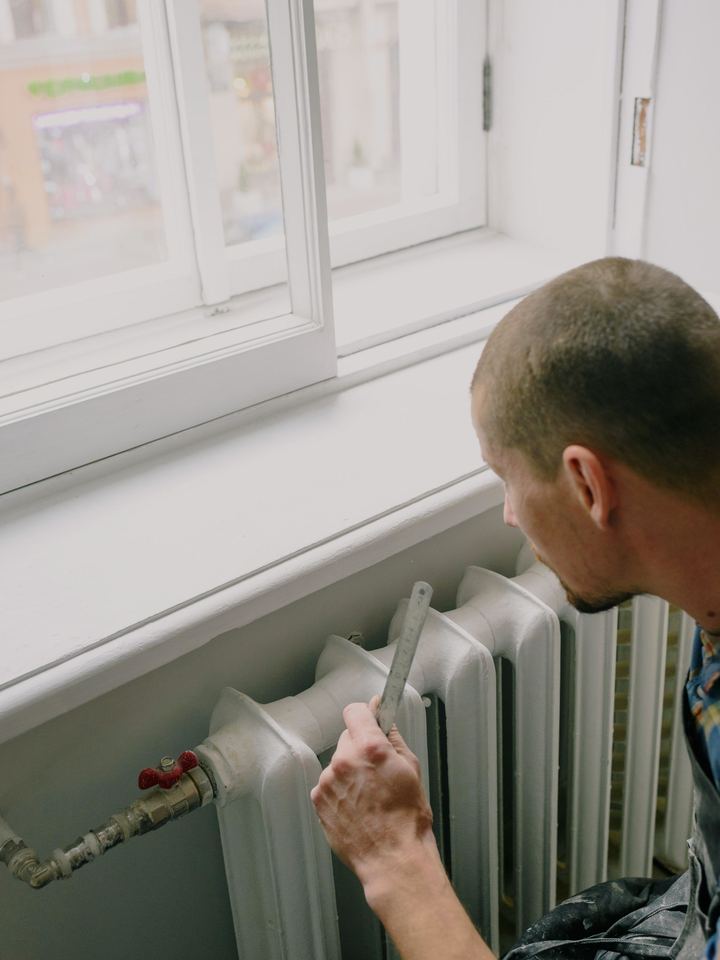 Handyman repairing a radiator under a bright window