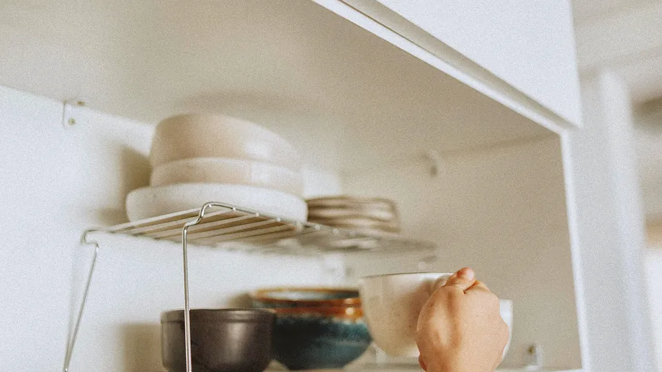 Stacked plates and bowls on an open cabinet shelf