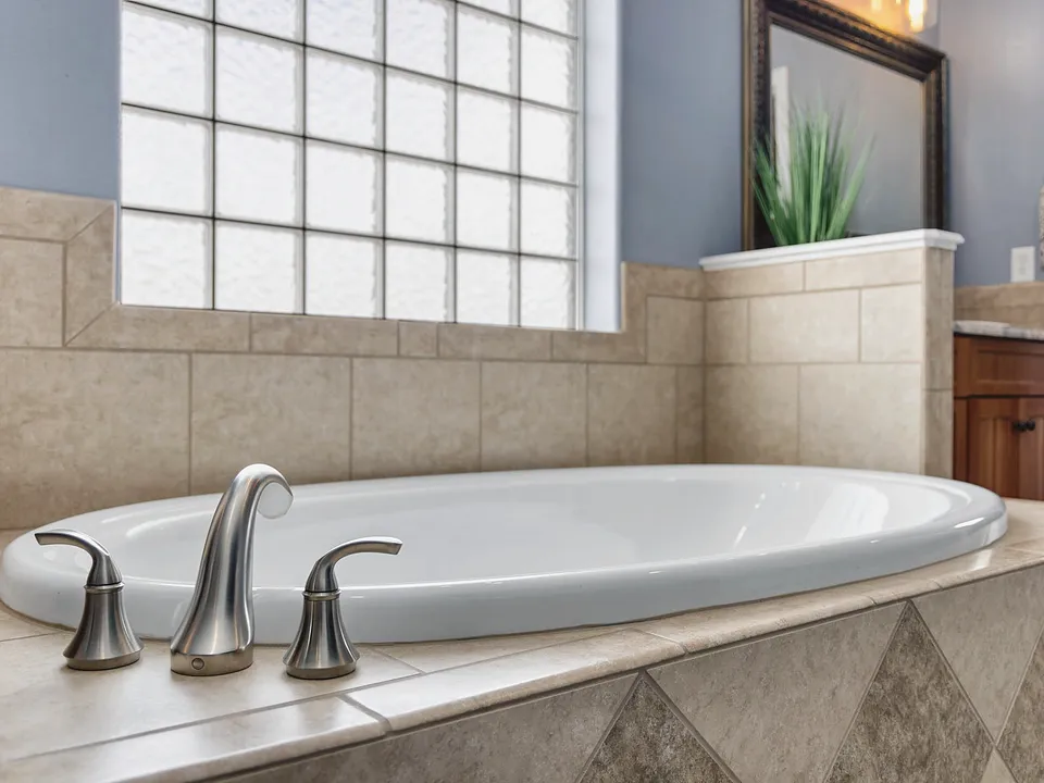 White tub with a deck faucet under a glass-block window