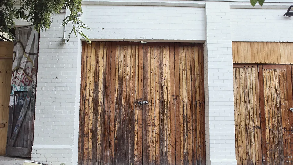 Pair of heavy wood plank doors set in a white wall