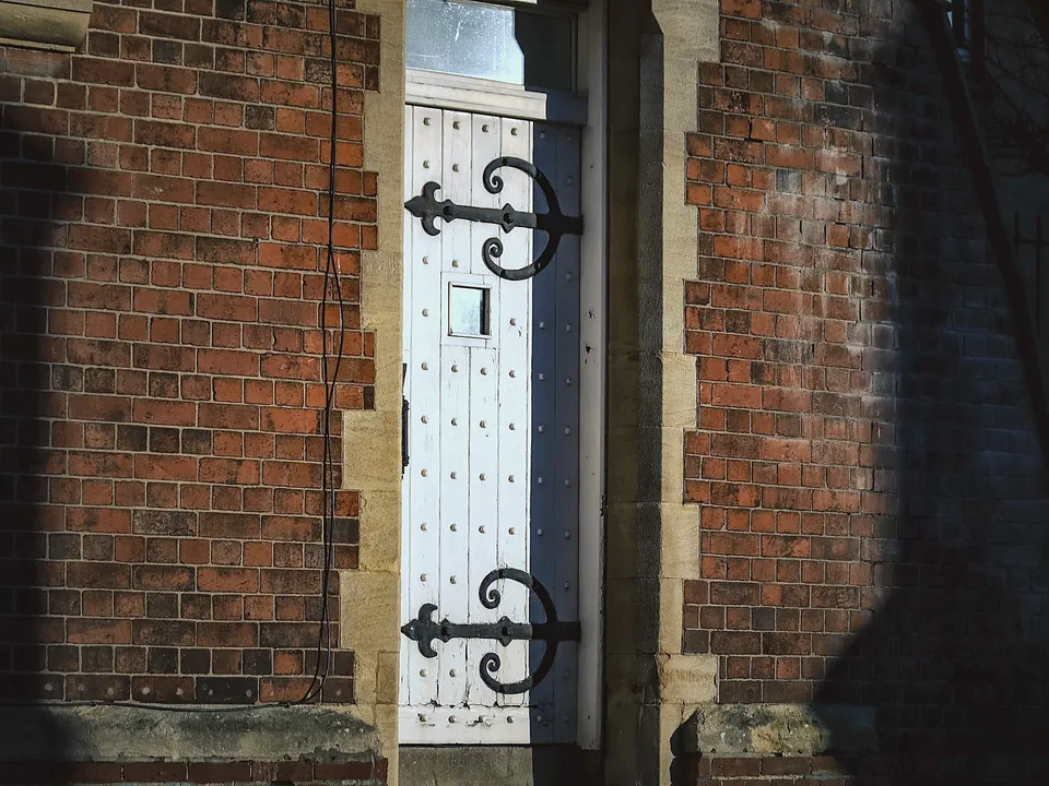 Black strap hinges on a dark plank door
