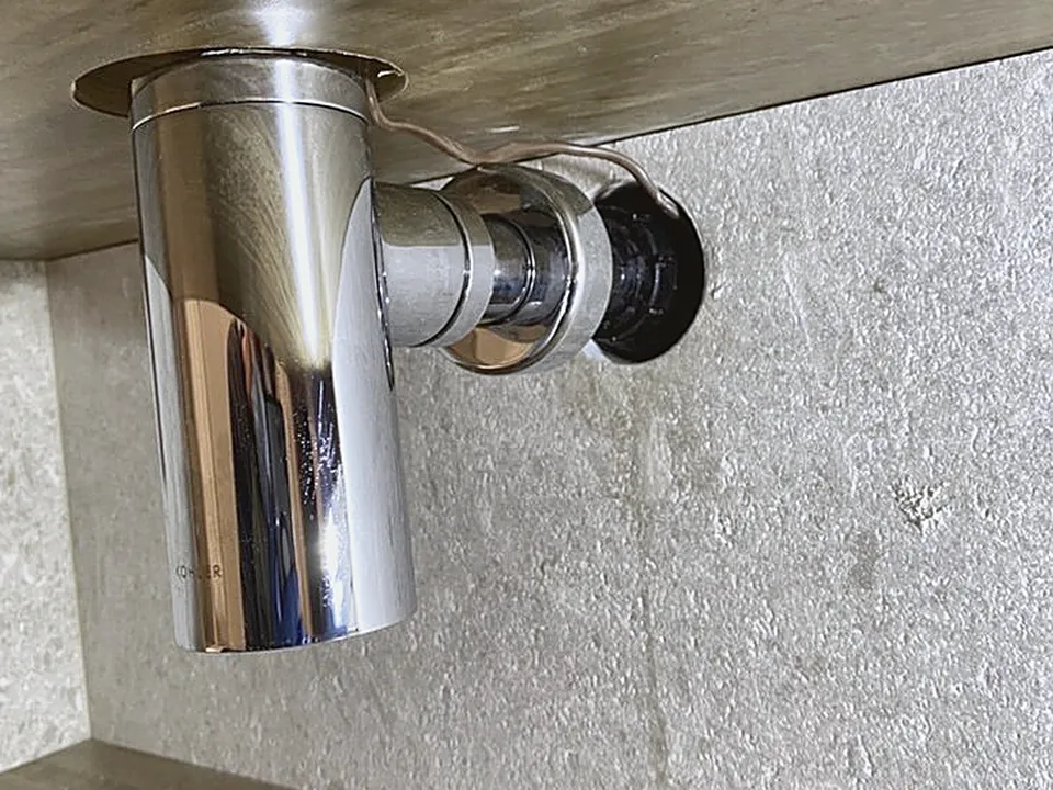 New chrome drain trap installed under a sink