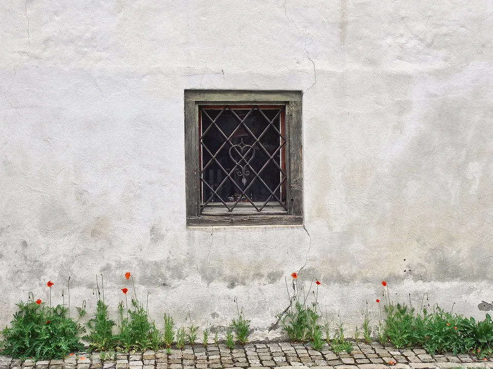 Small barred window in a thick white plaster wall