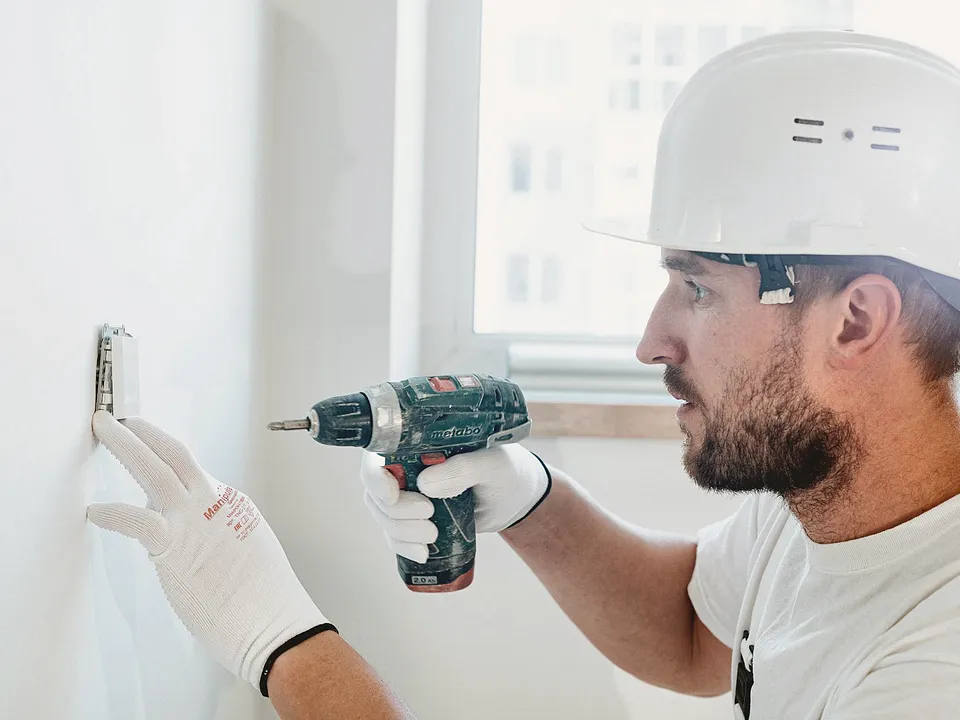 Worker drilling into a white wall