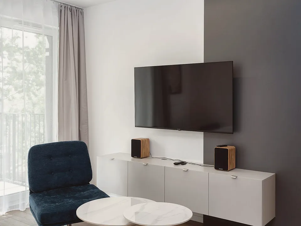 TV mounted on a gray wall above a white console