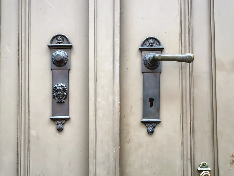 Vintage lever handles and keyhole plates on a pale door