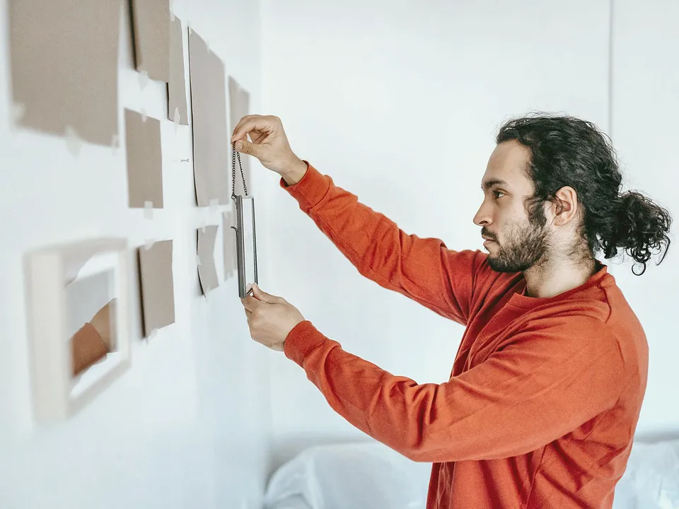 Man leveling framed pictures on a wall