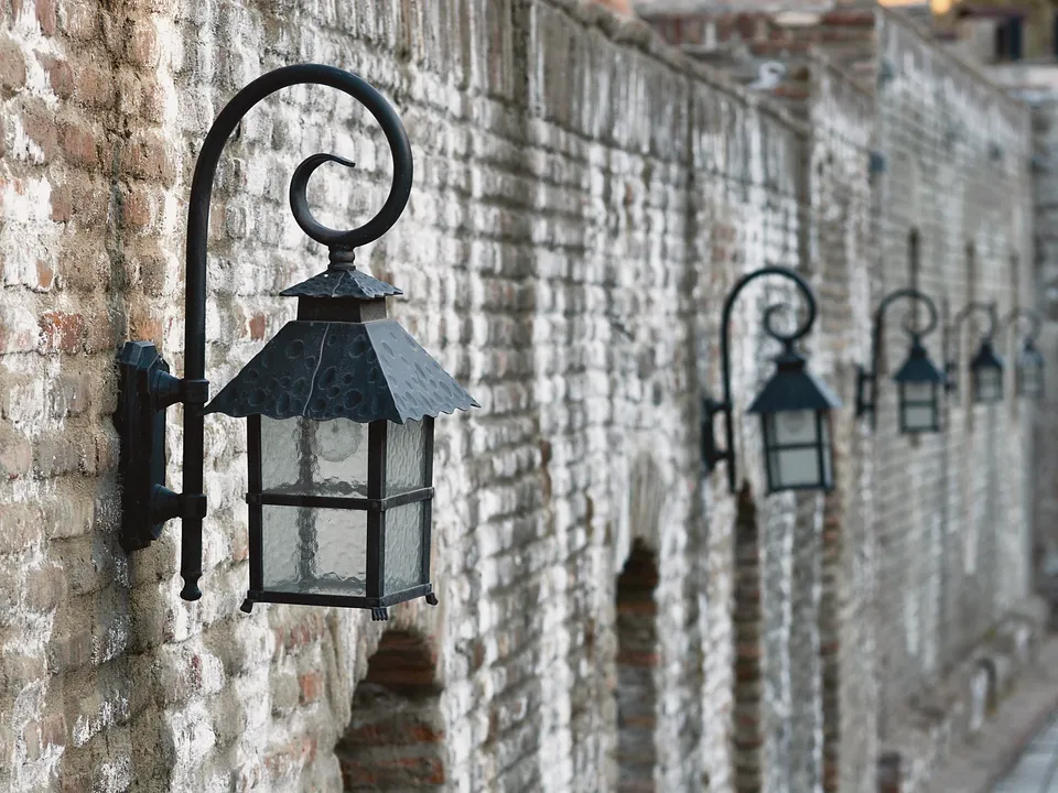 Wrought-iron wall lanterns along a stone wall