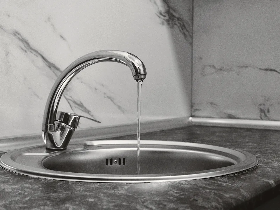 Chrome faucet running into a round steel sink