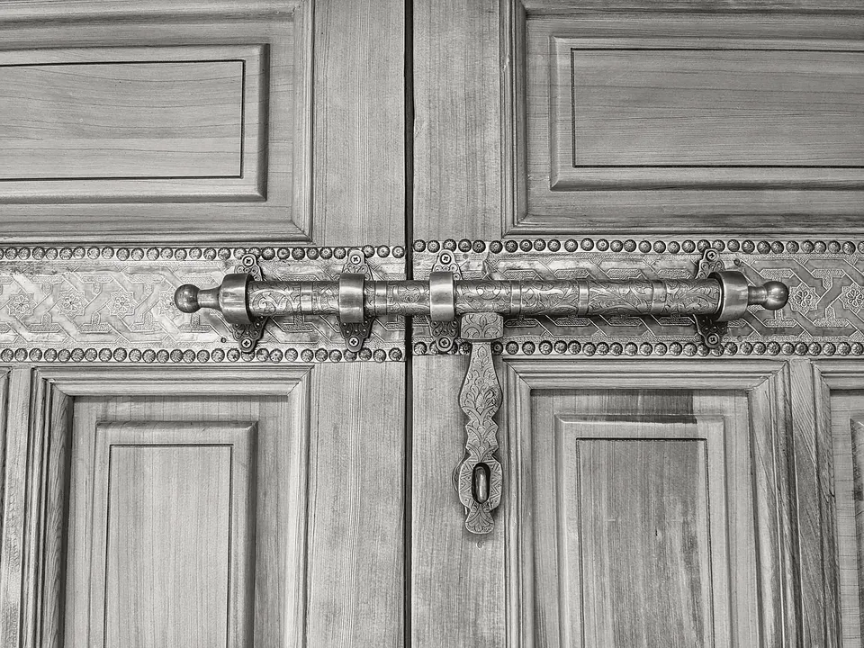 Old sliding bolt latch on a paneled wood door