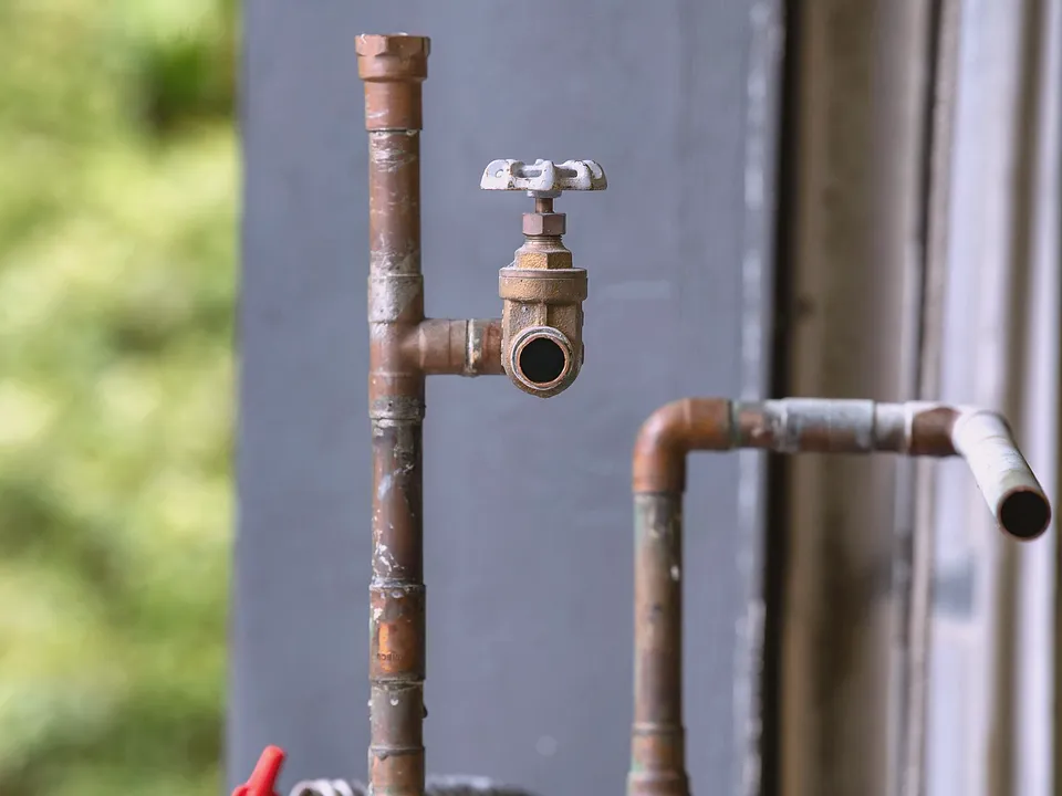 Old galvanized pipe and valve along a wall