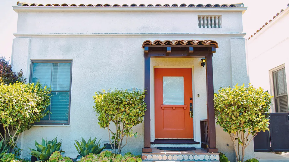 Small stucco house with an orange front door