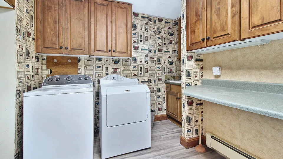 Laundry room with a top-load washer and dryer under wood cabinets