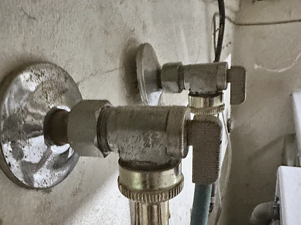 Washer shutoff valves on a wall with hoses connected