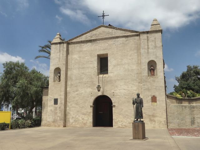 The front of Mission San Gabriel, with its arched church doorway and a statue in the courtyard