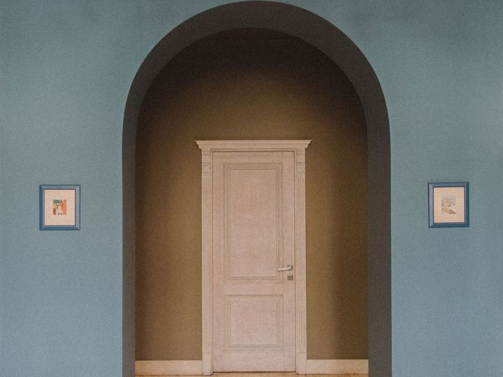 White paneled interior door seen through an arched opening in a blue wall