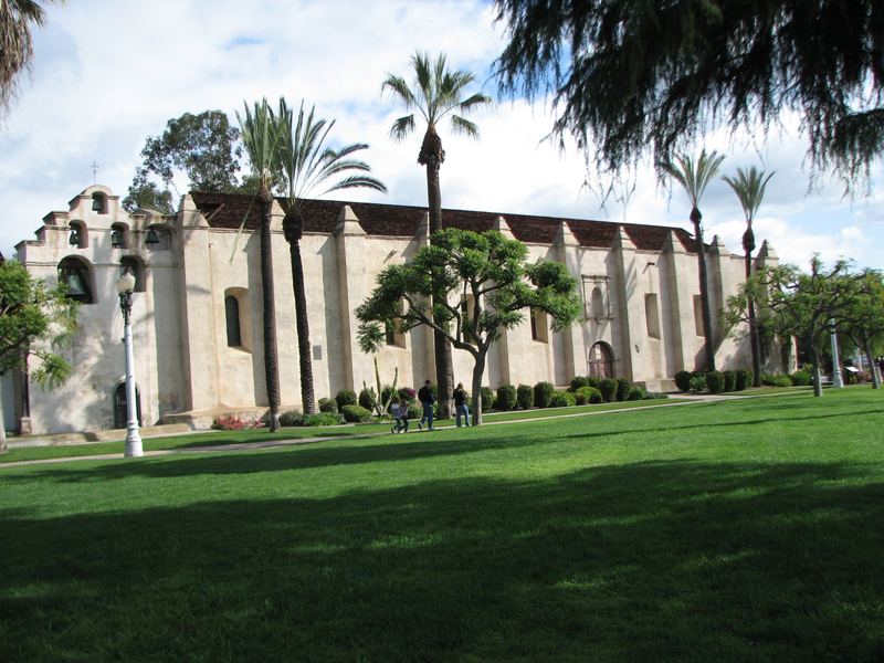 Mission San Gabriel Arcángel church facade with its bell wall and palms