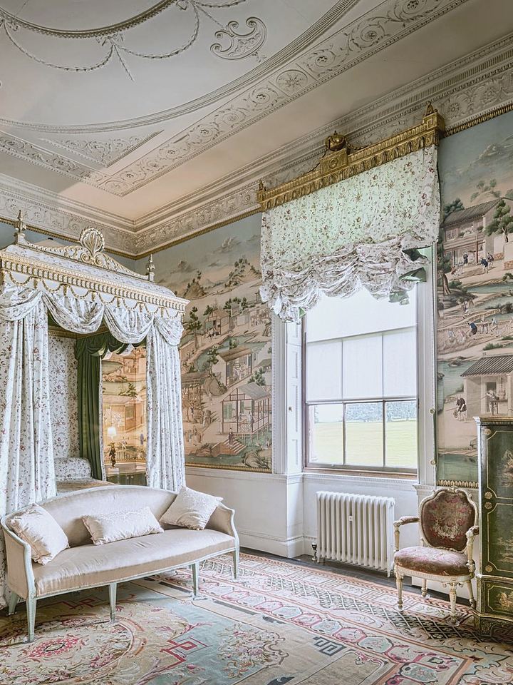 Historic room with a canopy bed, painted wallpaper and tall windows