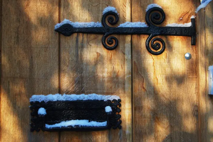 Black iron strap hinge and mail slot on a wood door