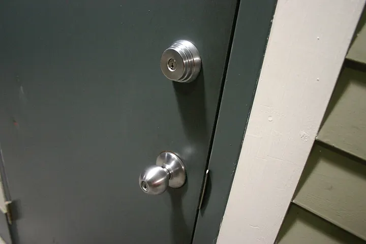 Gray door with a round knob and a deadbolt above it