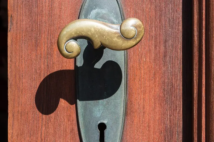 Brass lever handle and keyhole plate on a red door