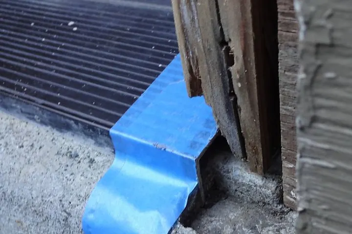 Rotted lower door frame above the sill, with blue tape on the threshold