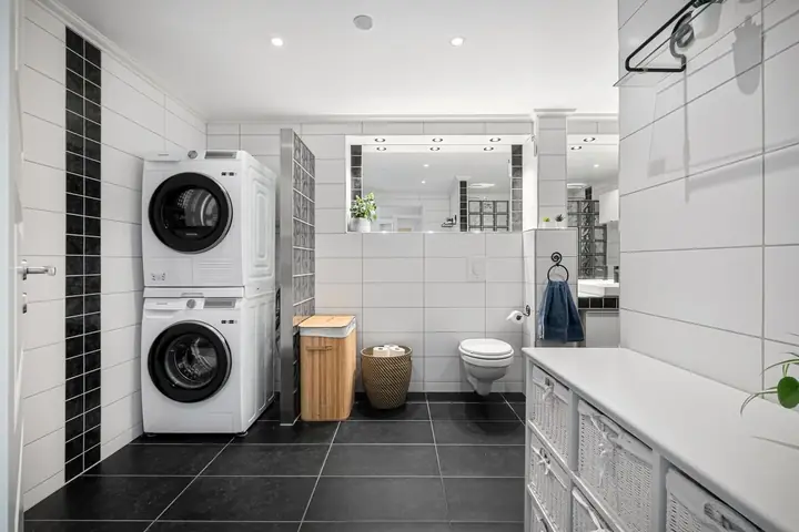 Stacked washer and dryer in a black and white tiled bathroom