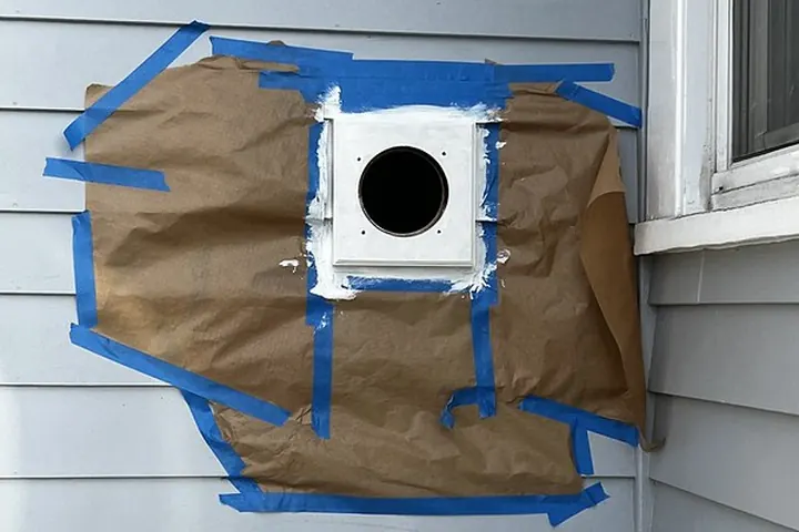 New dryer vent box taped into gray siding