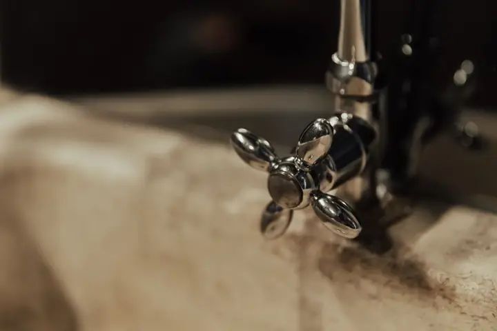 Old cross-handle faucet over a sink edge in warm light