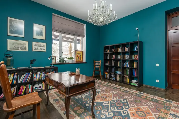 Teal room with a wood desk, chair and full bookshelves