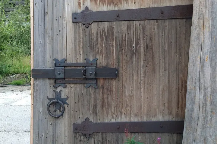 Wood plank gate with black strap hinges and a ring latch