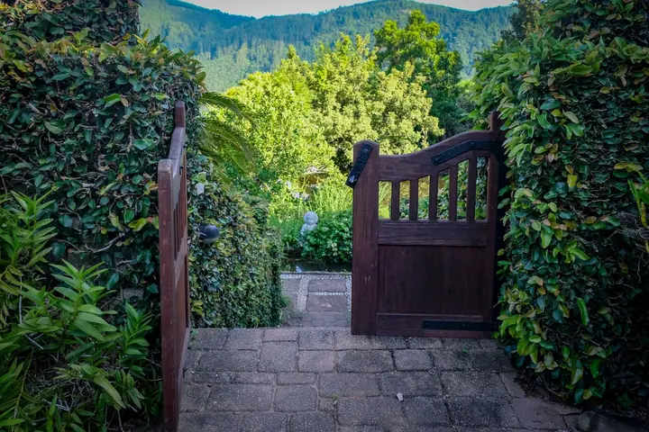 Open wooden gate opening onto a lush garden with mountain views