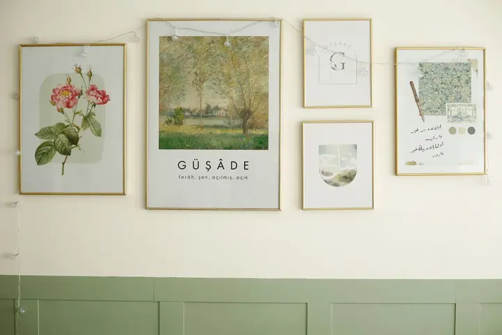 Framed botanical and landscape prints over a green wainscot