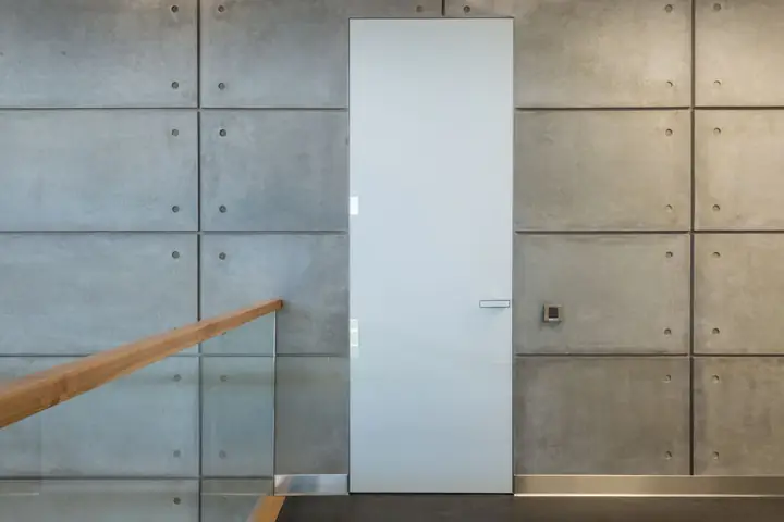 White door set in a concrete panel wall by a stair rail