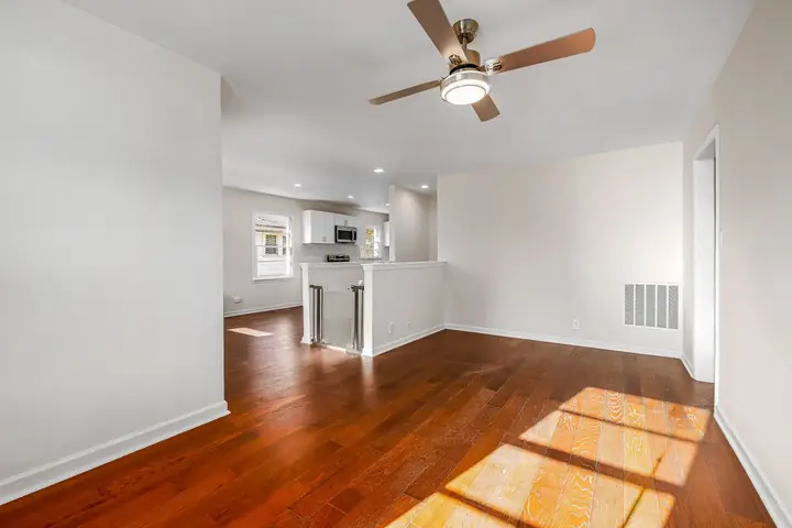 Empty living room with a ceiling fan and glossy wood floors