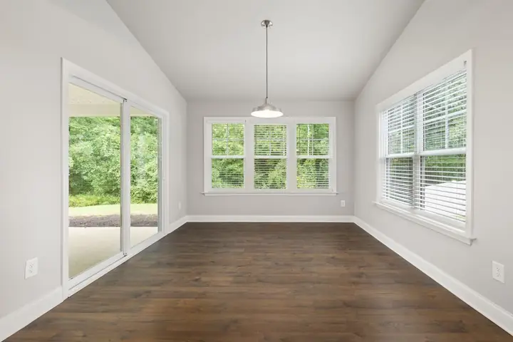 Empty room with dark wood floors and several large windows