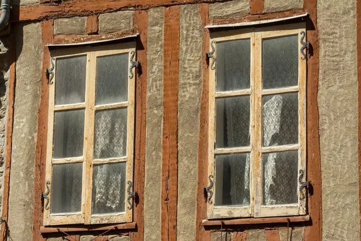 Close-up of rustic vintage windows with wooden frames on a traditional facade