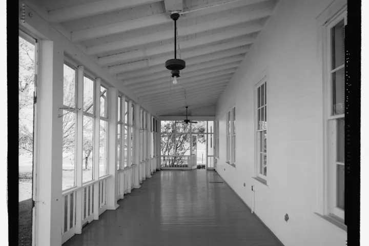 Long screened porch with wood floors and a ceiling light