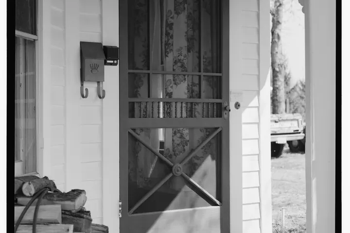Screen door with diagonal braces on a white porch