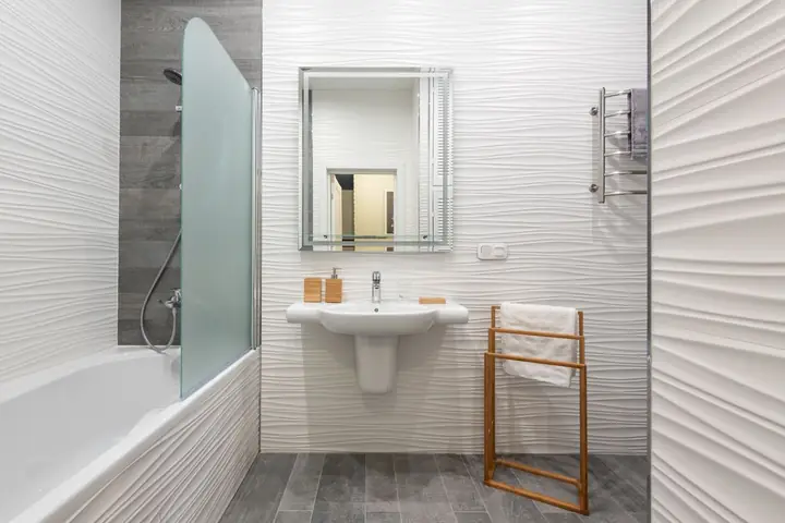 White tub and pedestal sink with a mirror and towel rack