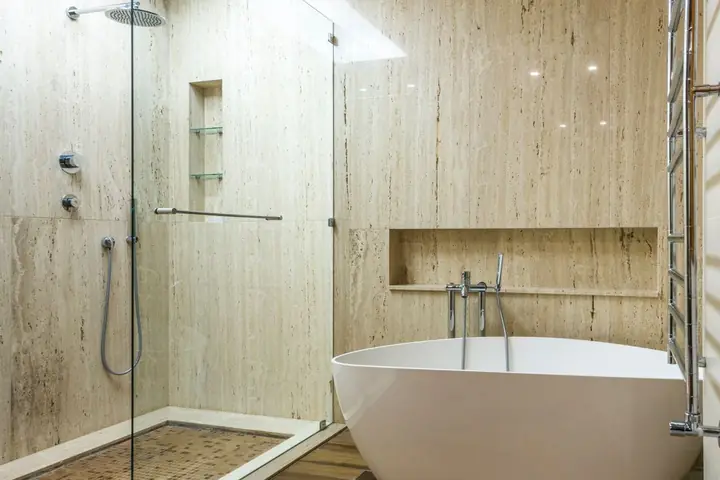 Glass shower beside a freestanding tub in a wood-look bathroom