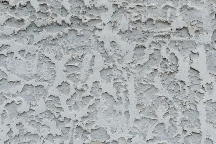 Closeup of rough textured cracked surface of aged stucco wall as abstract background