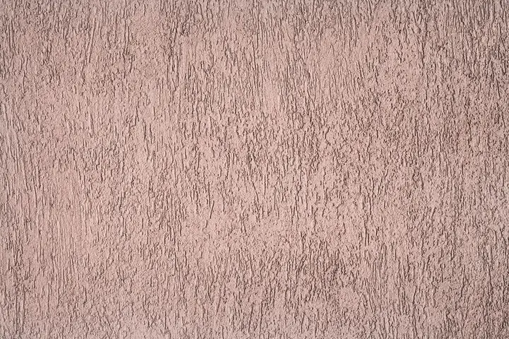 Close view of rough pink stucco wall texture