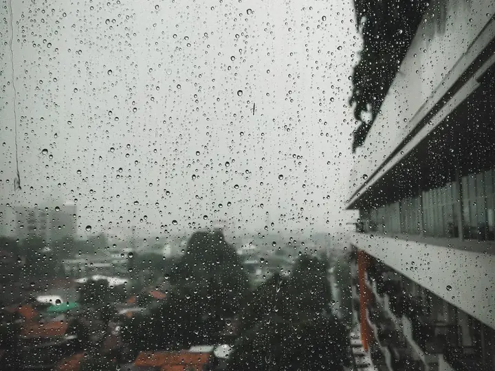 Raindrops on a window with an overcast urban view