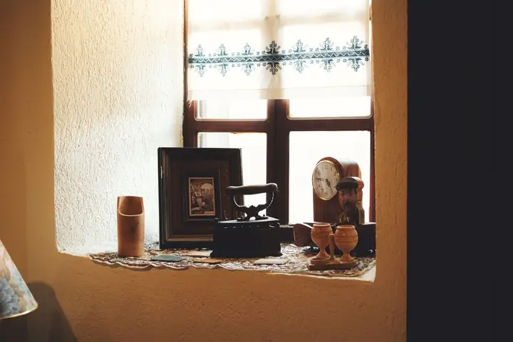 An indoor window sill decorated with vintage antiques and soft natural lighting